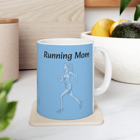 A durable white ceramic Running Mom - Ceramic Mug 11oz from Printify with an illustration of a running woman and the text "Running Mom" on it, positioned on a coaster next to a bowl of fruit on a kitchen counter.