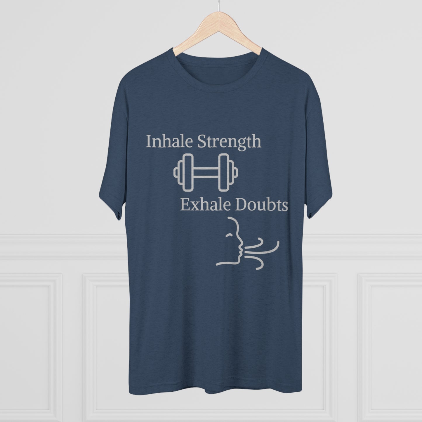A navy blue motivational Inhale Strength Exhale Doubt w Images - Unisex Tri-Blend Crew Tee by Printify on a hanger featuring the text "inhale strength, exhale doubts" with graphics of a dumbbell and swirling lines symbolizing breath.