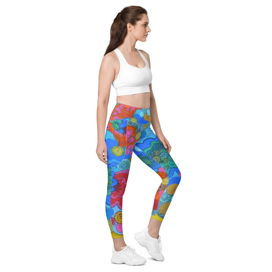 A woman stands in profile wearing a white sports bra, Blue Sky Runners' Coral leggings with pockets featuring a vibrant floral design, and white sneakers. Her brown hair is tied back in a ponytail. She looks straight ahead with a neutral expression against a plain white background.